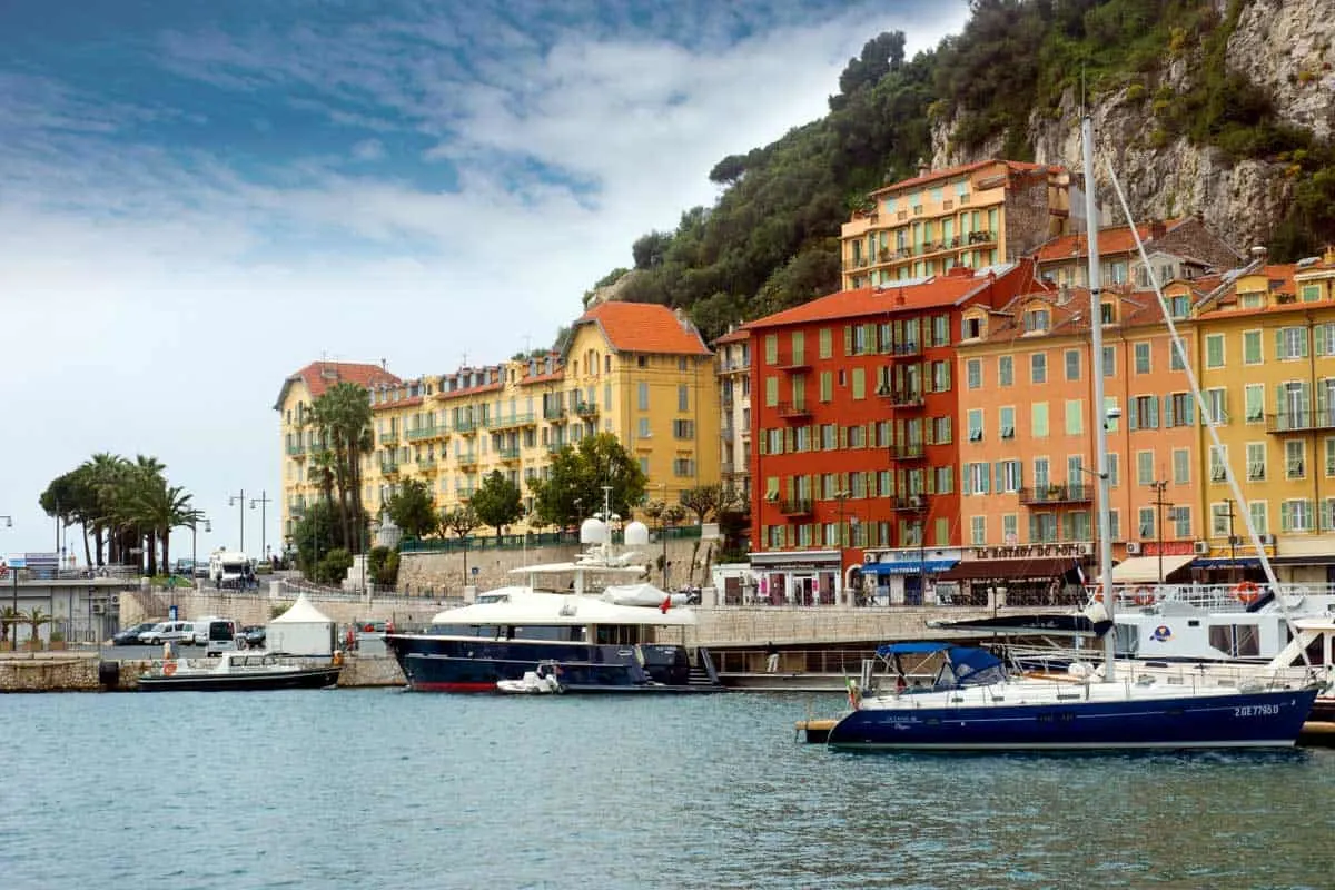 Yachts moored in front of colourful buildings in Nice harbour in April. 