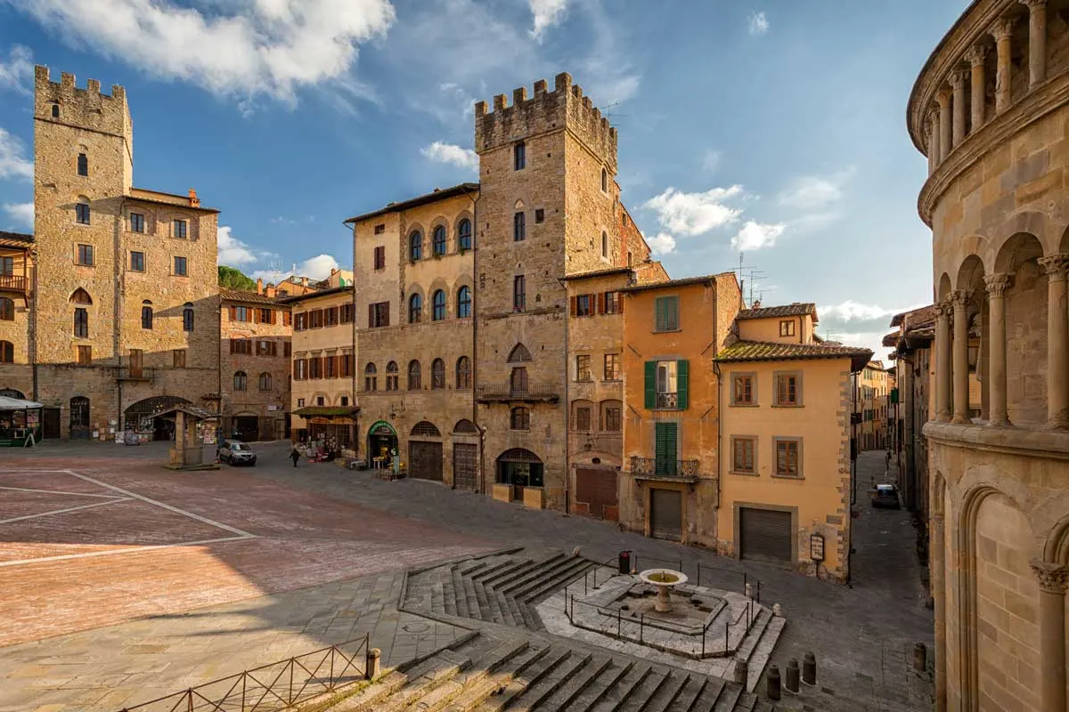 The main square of Arezzo Italy surrounded by stone medieval buildings. 