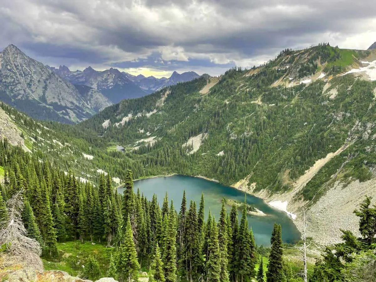 View over a bright blue crater lake surrounded by forest.