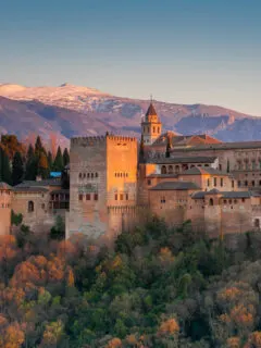 Alhambra palace, Granada, Spain at sunset with snow capped mountains in the distance.
