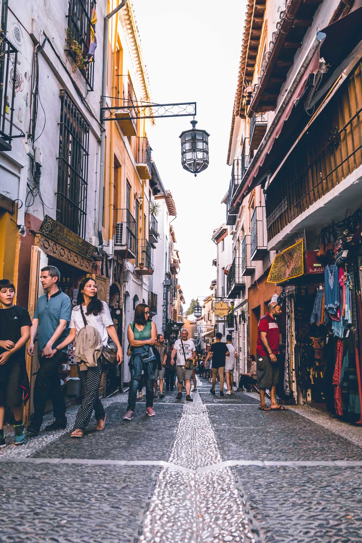 People walking down an atmospheric street in old town Granada Spain. 