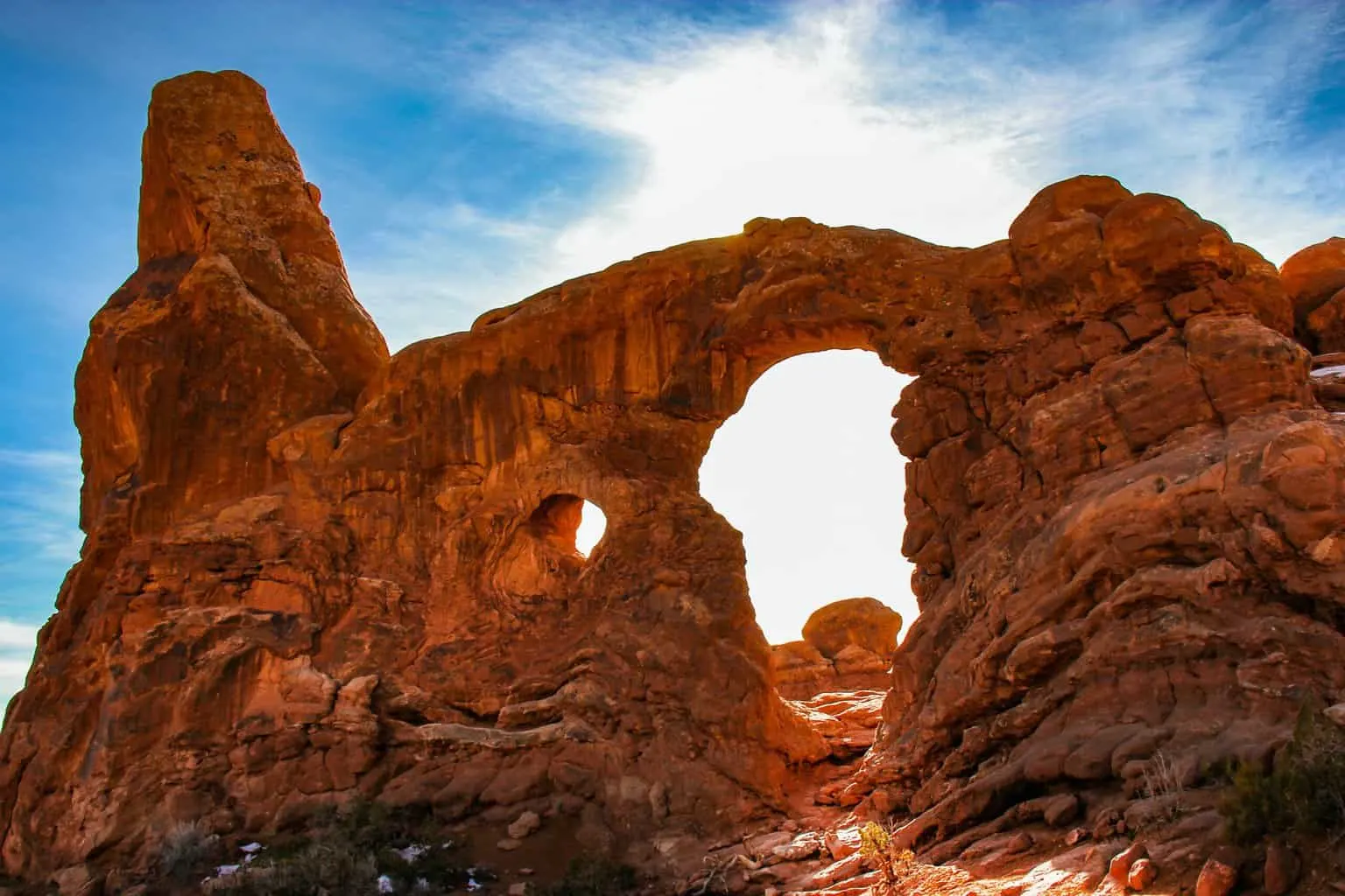 Snow on the red rock arches of Arches National Park on a winter hiking day