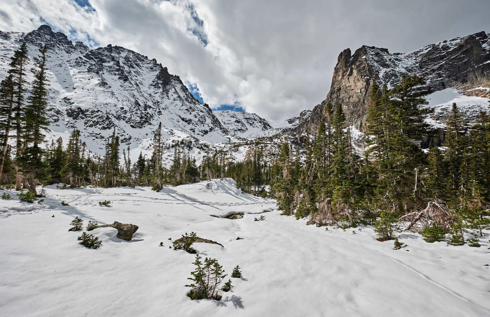 A frozen lake and snowy peaks on a winter hiking trail in Rocky Mountain National Park