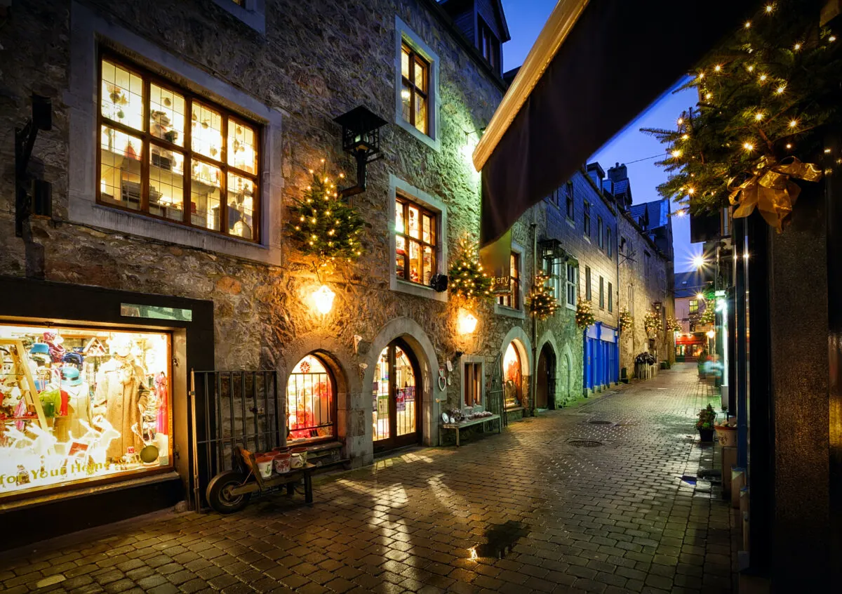 Stores dressed for Christmas in lights and decorations on a city street at night