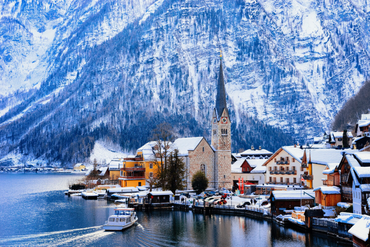 Winter scene at Hallstatt near Salzburg, in Austria, Europe. Church steeple with snow-capped mountains in the backdrop