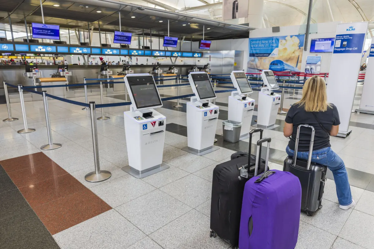 Woman sitting on luggage at an airport luggage check station