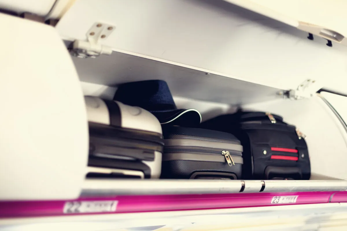 Three carry-on luggage bags in an overhead compartment on an airplane