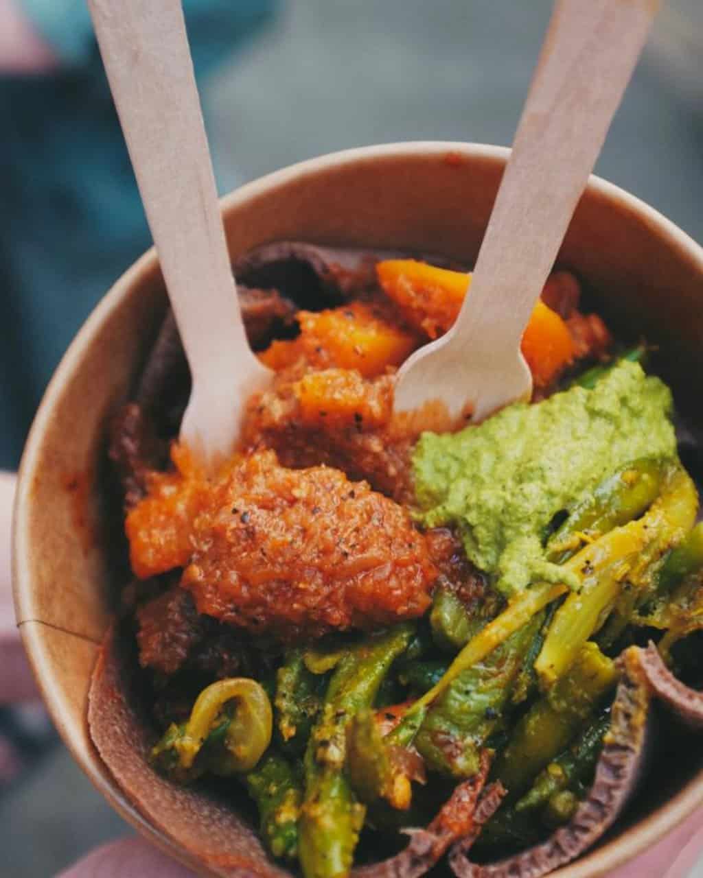 Bowl of food from the Maltby Street Food Market filled with sweet potato, guacamole and cooked vegetables