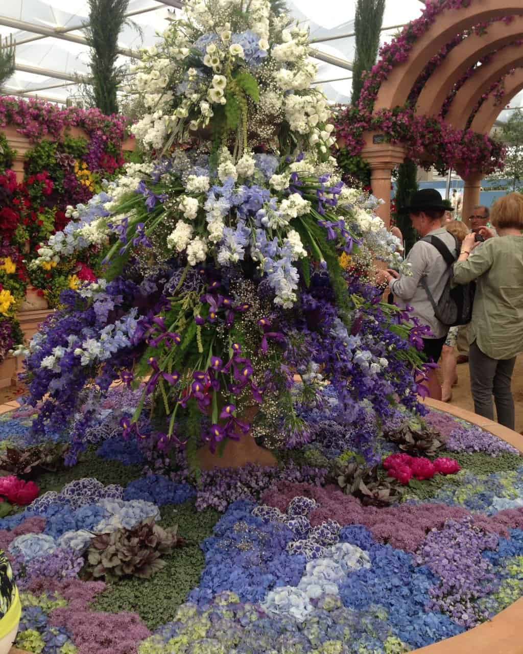 people taking photographs of a large multicolor flower arrangement in Chelsea Flower Show in London, UK