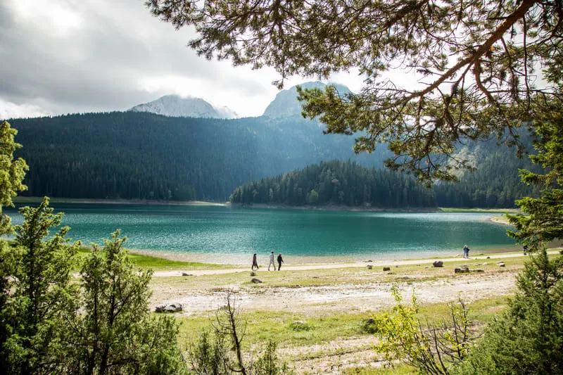 Walkers beside a frozen mountain lake in Montenegro in winter