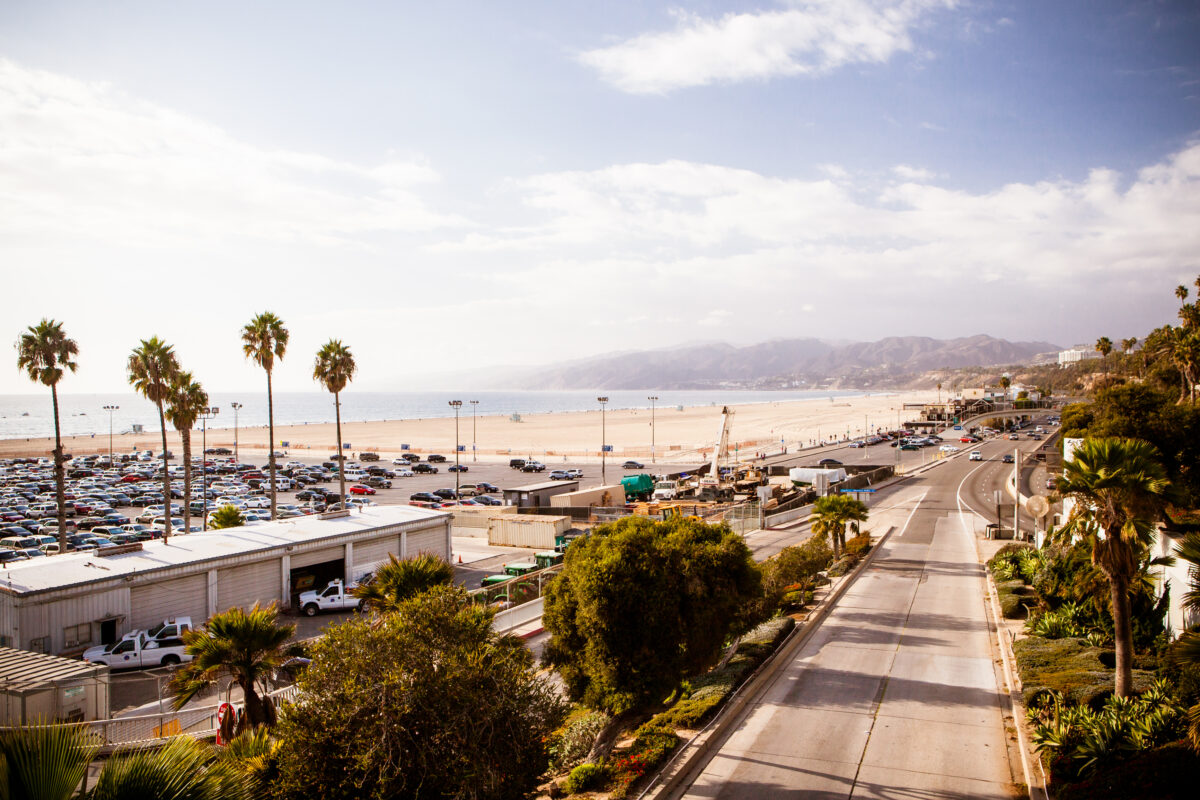 View of Santa Monica Highway with ocean and mountains in the backdrop on a partly sunny day