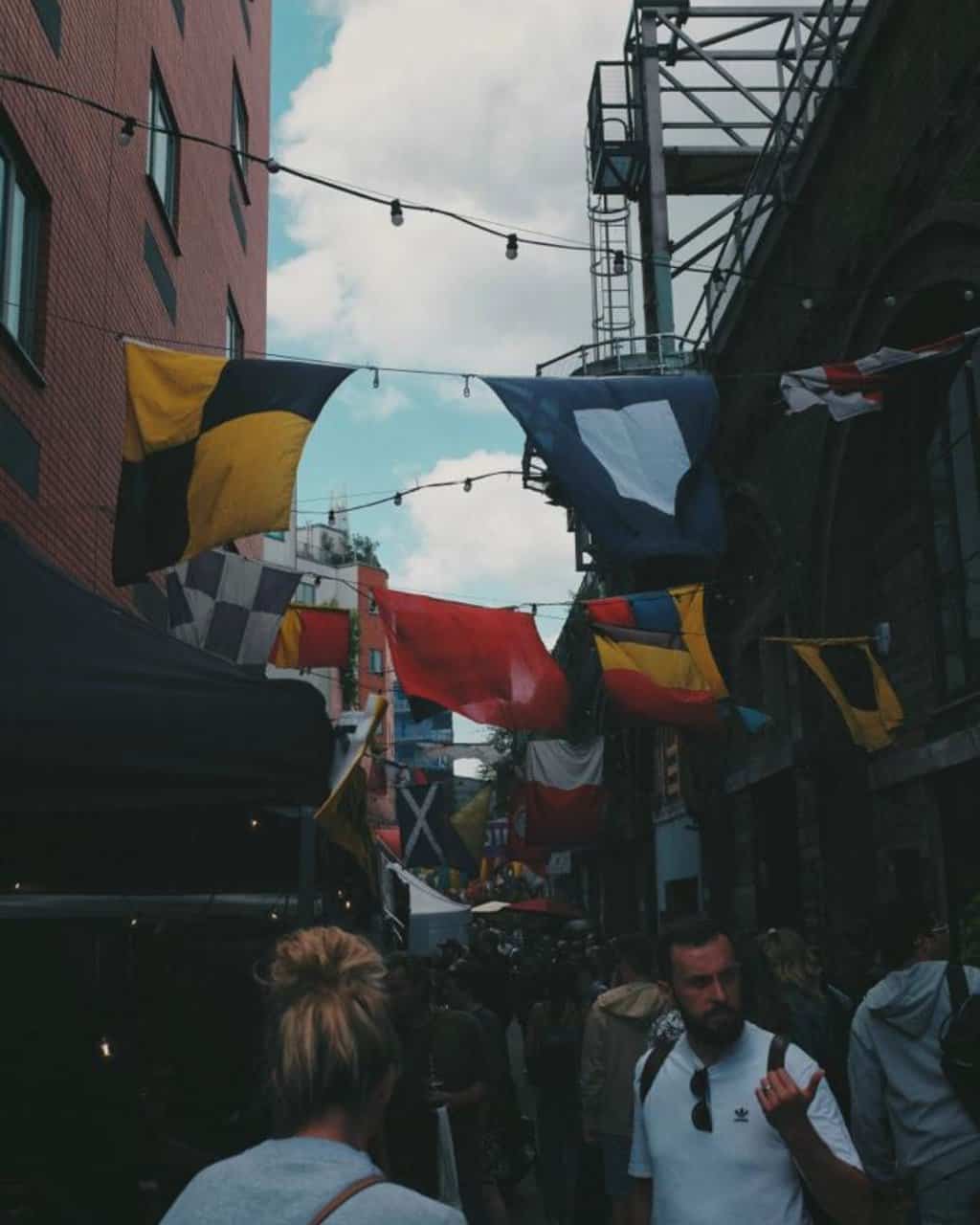 Crowded marketplace with flags at Maltby Street Market in London, UK