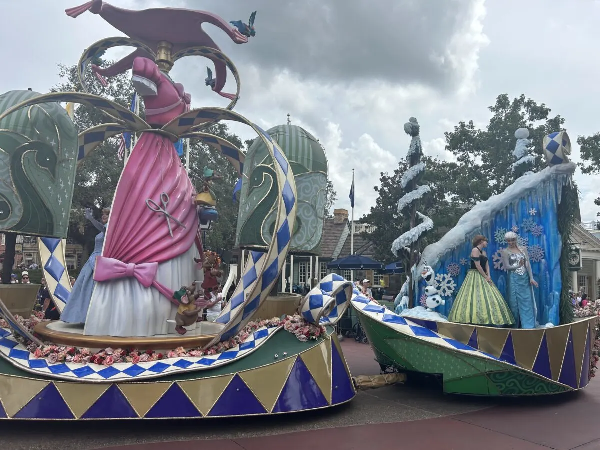 Disney parade float with cinderella's dress on one float and Elsa and Ana on another