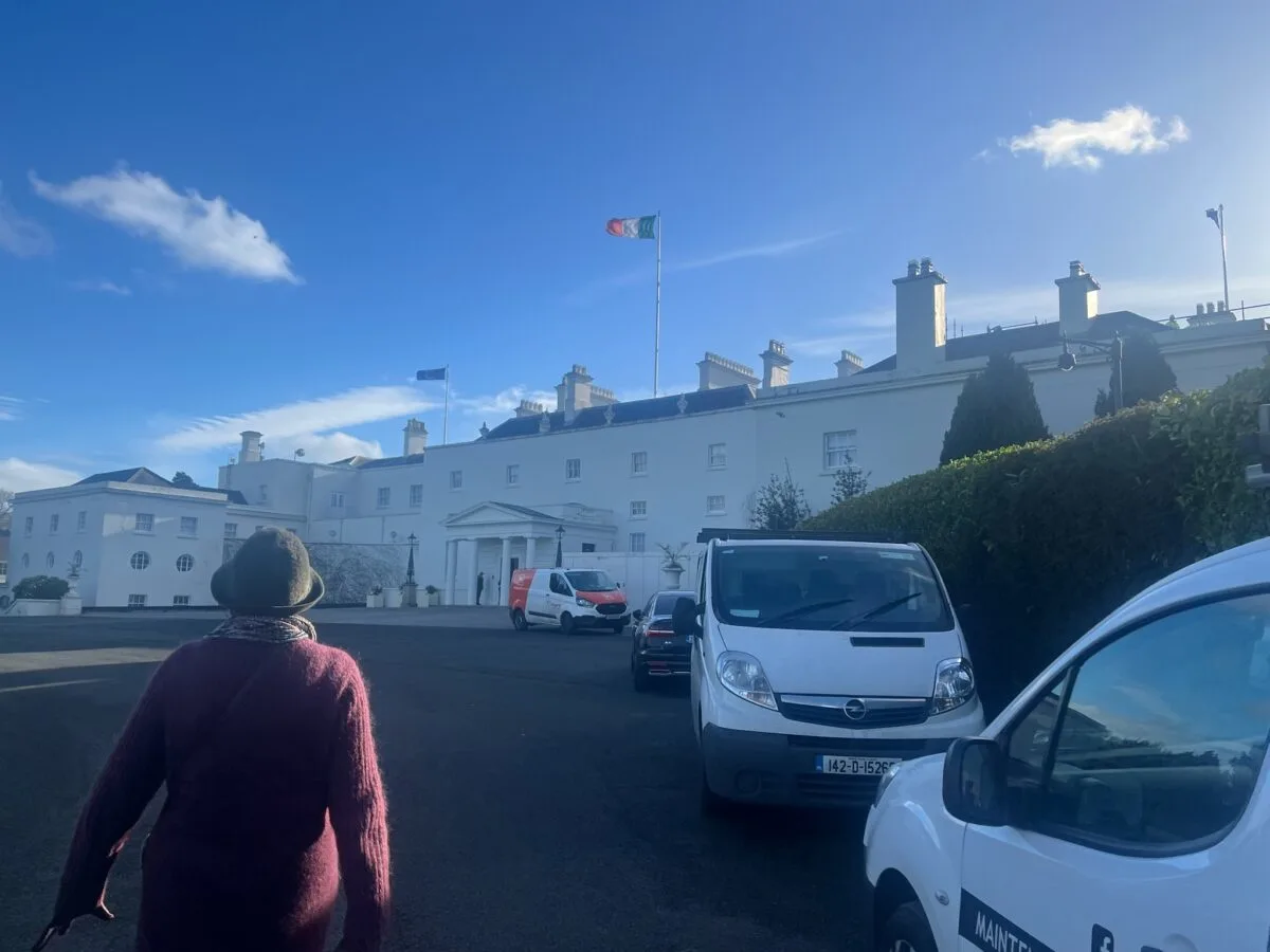 Exterior photo of the Ireland's President's house. White vehicles outside and a person walking. Galway Activities.