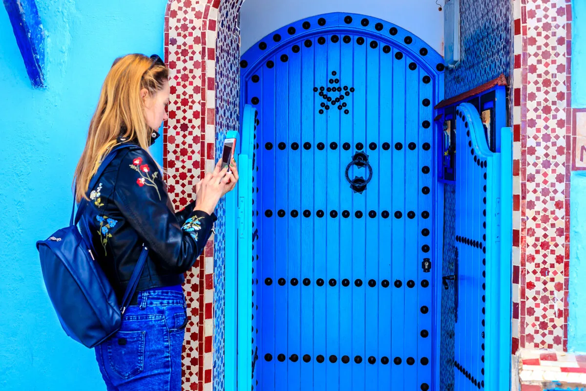 woman taking photo of a blue door in Morocco