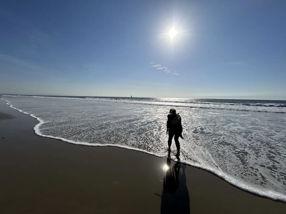 Woman standing on the sand at the low tide of the ocean