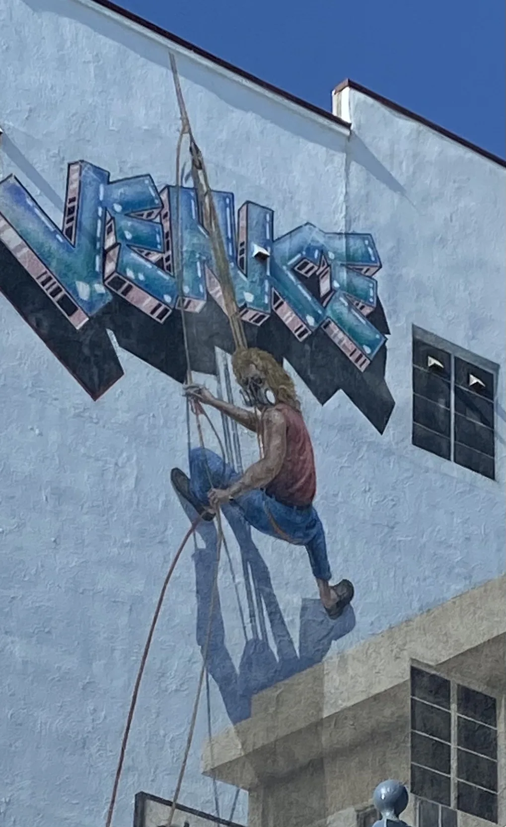 Pianted wall at Venice Beach in California. Wall is a picture of a man scaling the wall up to the words Venice