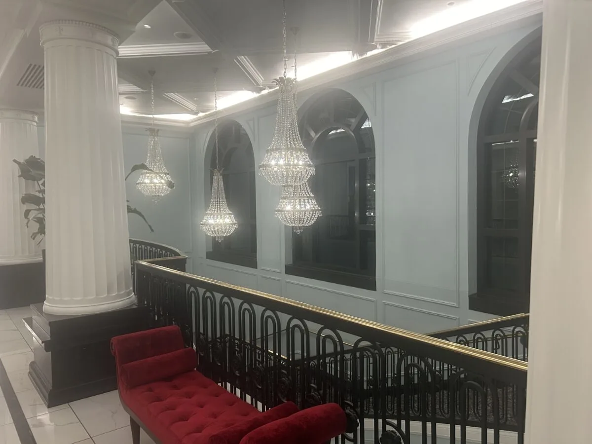 Interior photo of Hotel Carmichael in Carmel, Indiana. Showing staircase, hanging chandeliers and a red velvet couch