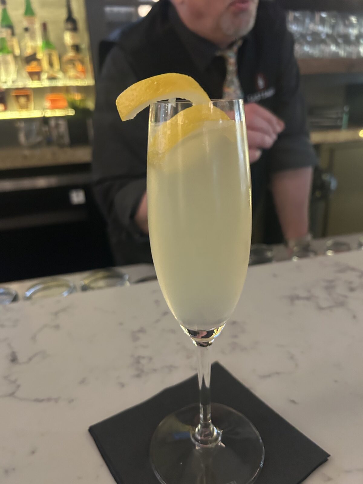 Photo of drink in a champaine glass with a twisted lemon peel