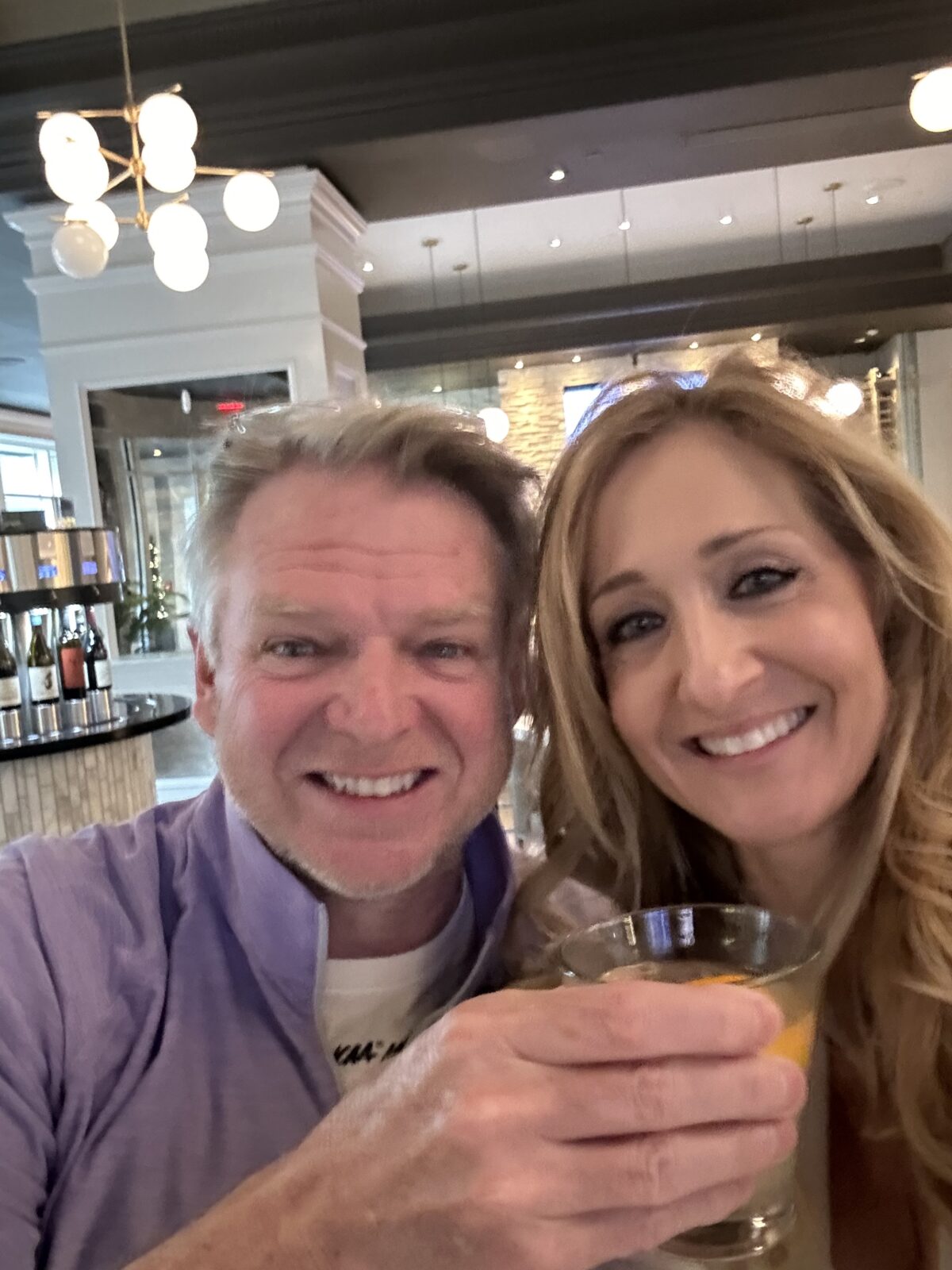 Man and woman smiling and toating with drinks at Tastings Wine Bar in downtown Indianapolis