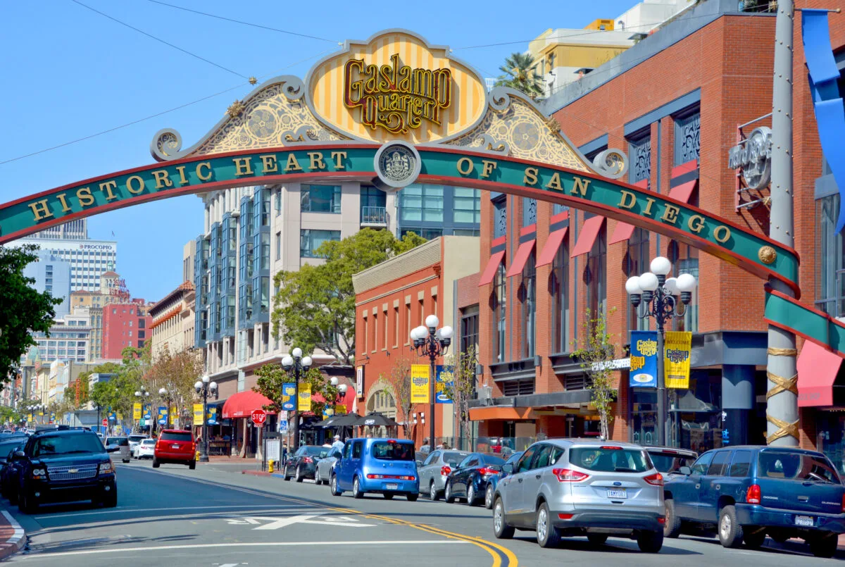 Entrance to The Gaslamp Quarter in California. Sign arching over the street way with cars in the street and city buildings on a sunny day