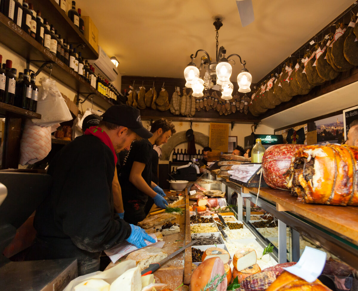 Meat market in Italy. Men working behind the counter making sandwiches