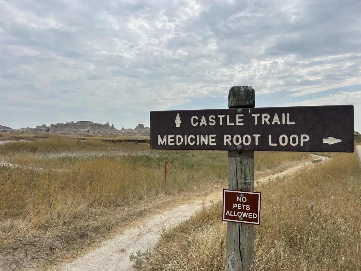 Trail sign for medicine root loop and castle trail within badlnads national park. background of flat and dry landscape