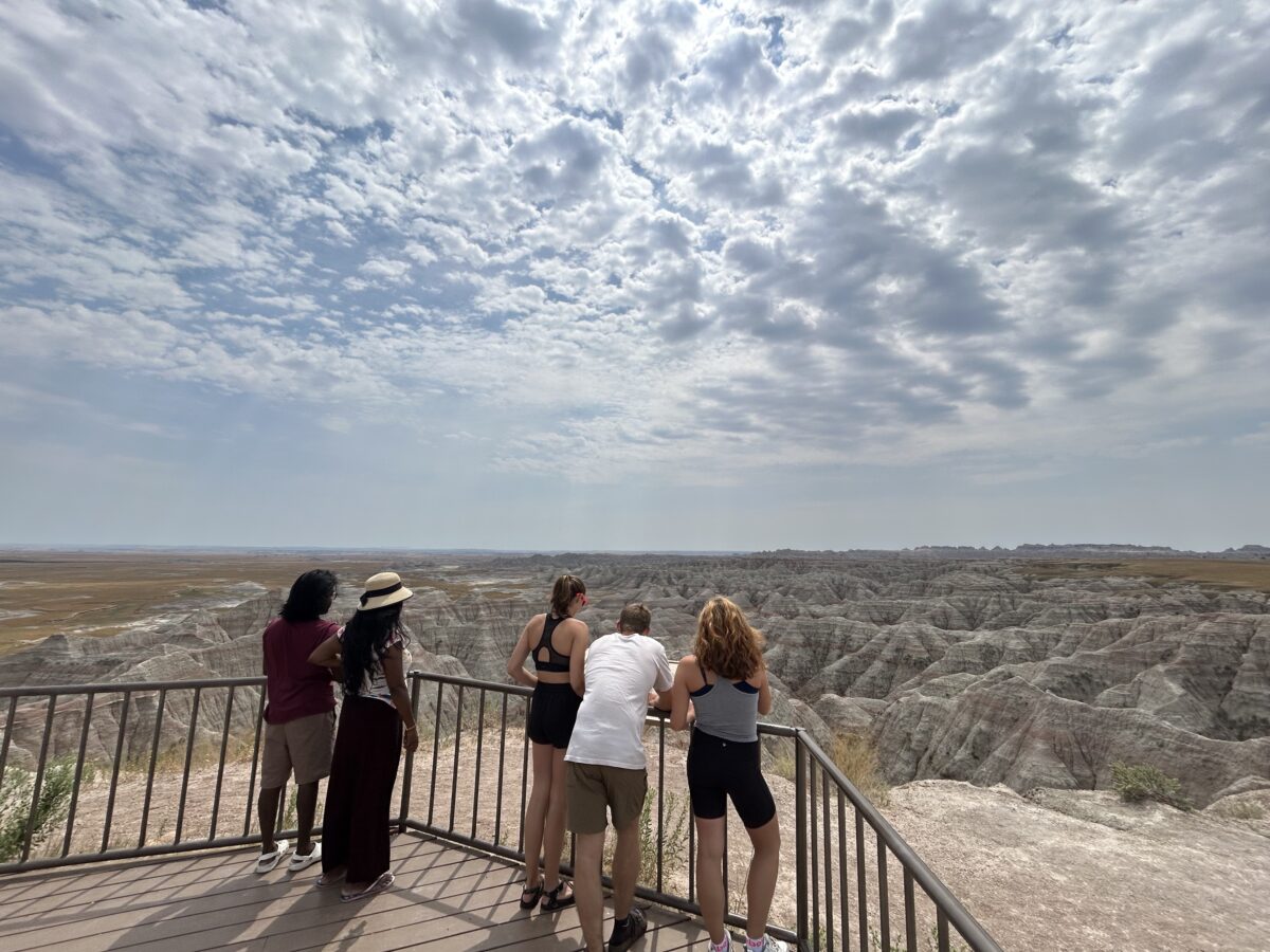 People overlooking rocks at Badlands National Park from an overlook platform on a sunny day