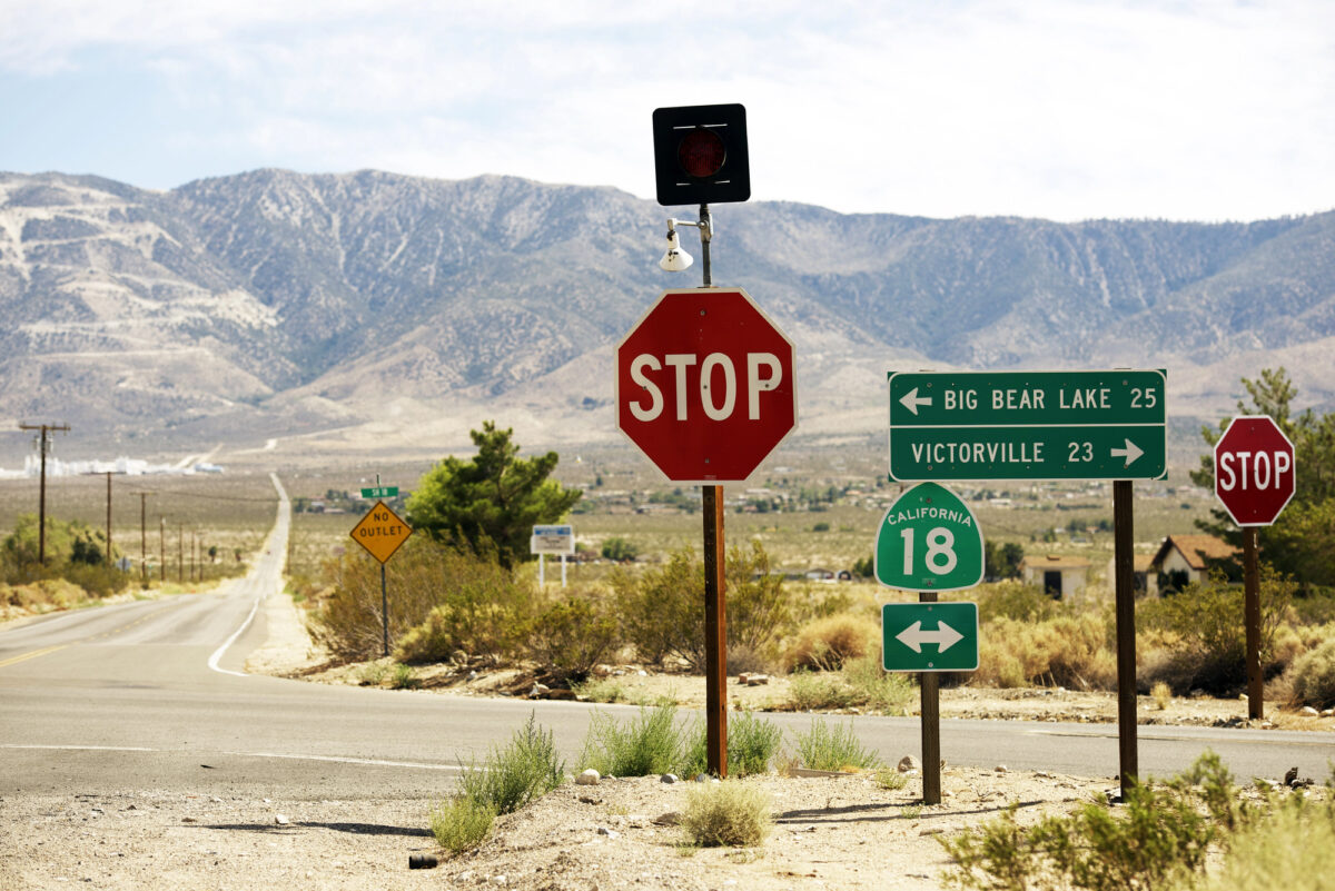 A stop sign and directional street signs to Big Bear Lake and Victorville in California