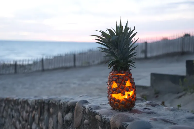 jack-o-lantern carved pineapple on the beach