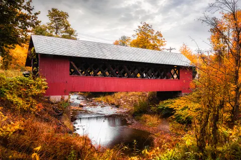 beautiful red cofered bridge surrounded by changing leaves in Vermont