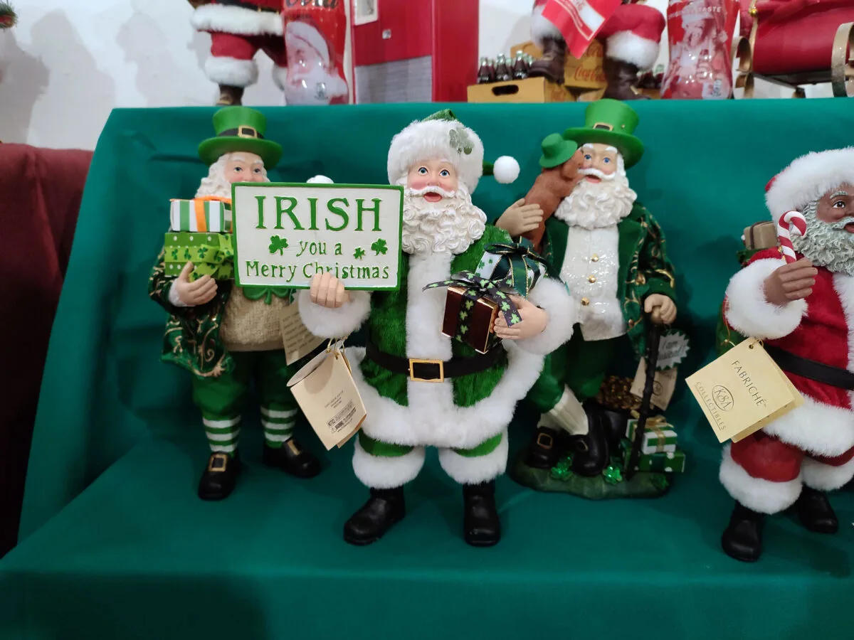 Irish market santas and puppets dressed in green and red sants suits holding a merry christmas sign