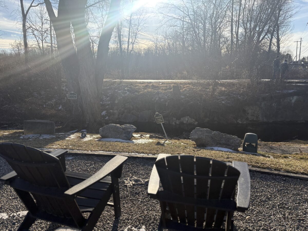 2 outdoor chairs sitting alongside Saucon Creek in Lehigh Valley, PA on a sunny day