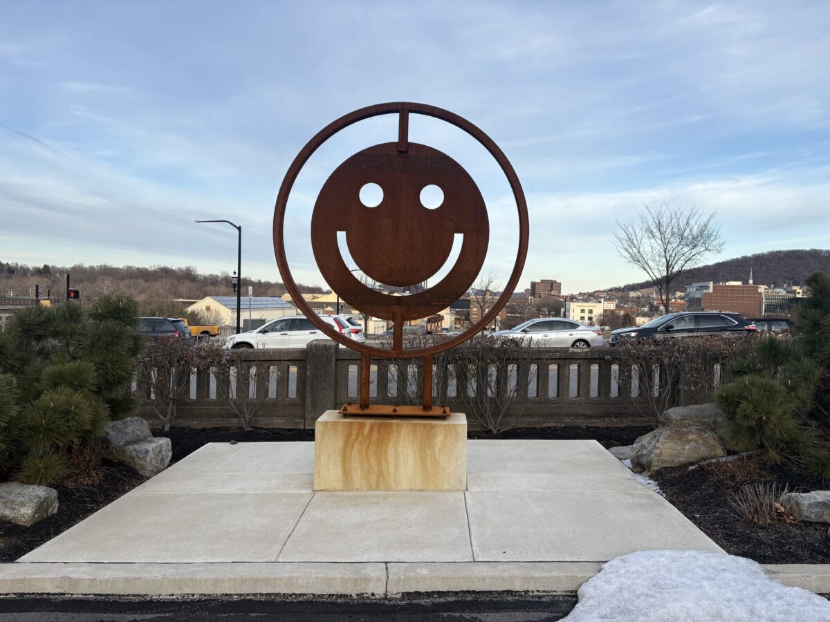 Rustic smile iron statue on a marble slab sitting upon a cement patio area with a sunny background