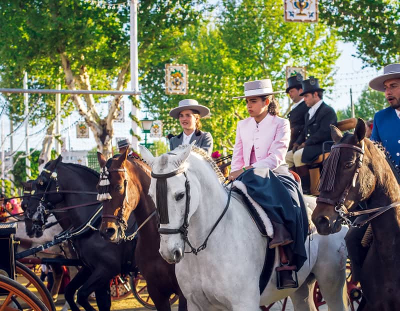 women riding horses dressed in traditional Spanish clothing in Seville celebrating the Seville April Fair