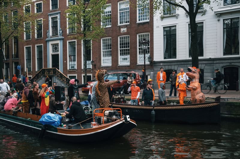 people dressed in orange on boats in a canal in Amsterdam Netherlands celebrating King's Day 