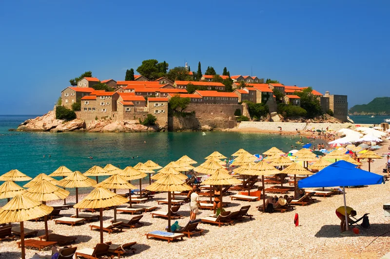 sunbathers under umbrellas on the beach overlooking the ocean in Montengro