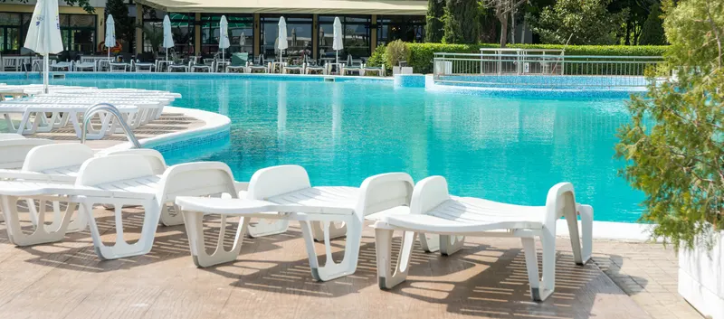 white lounge chairs in front of crystal blue pool