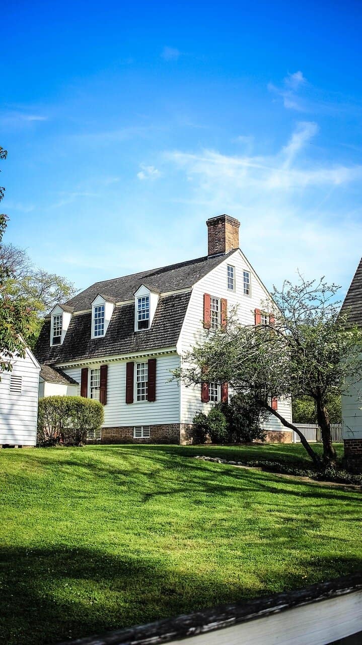 white colonial home with blue sky and green grass